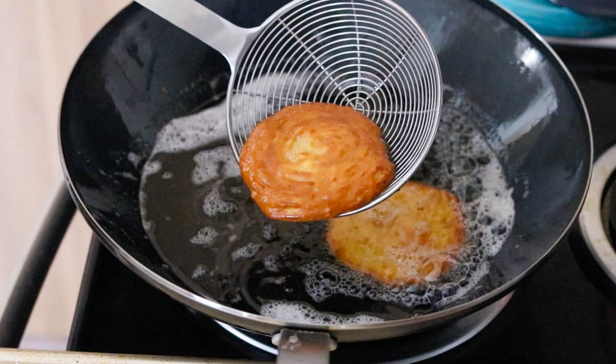 zeppole in a spider strainer over a wok