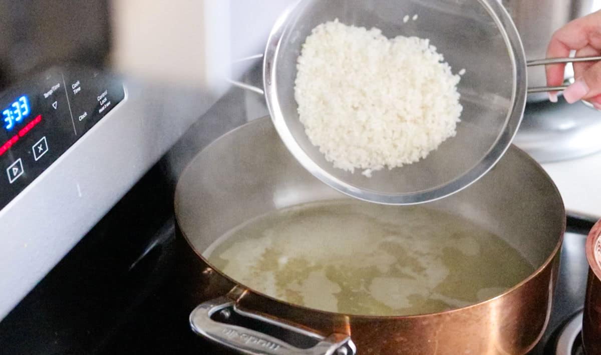 Kristin is adding the washed rice to the rondeau containing chicken broth
