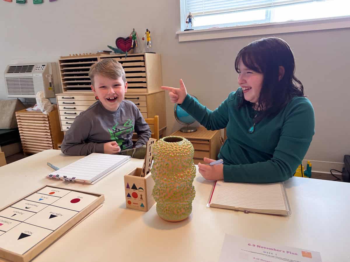 Kaia is pointing at Noah for a demonstrative adjectives lesson