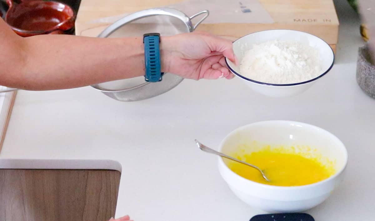Kristin is adding flour to an egg mixture for pastry cream