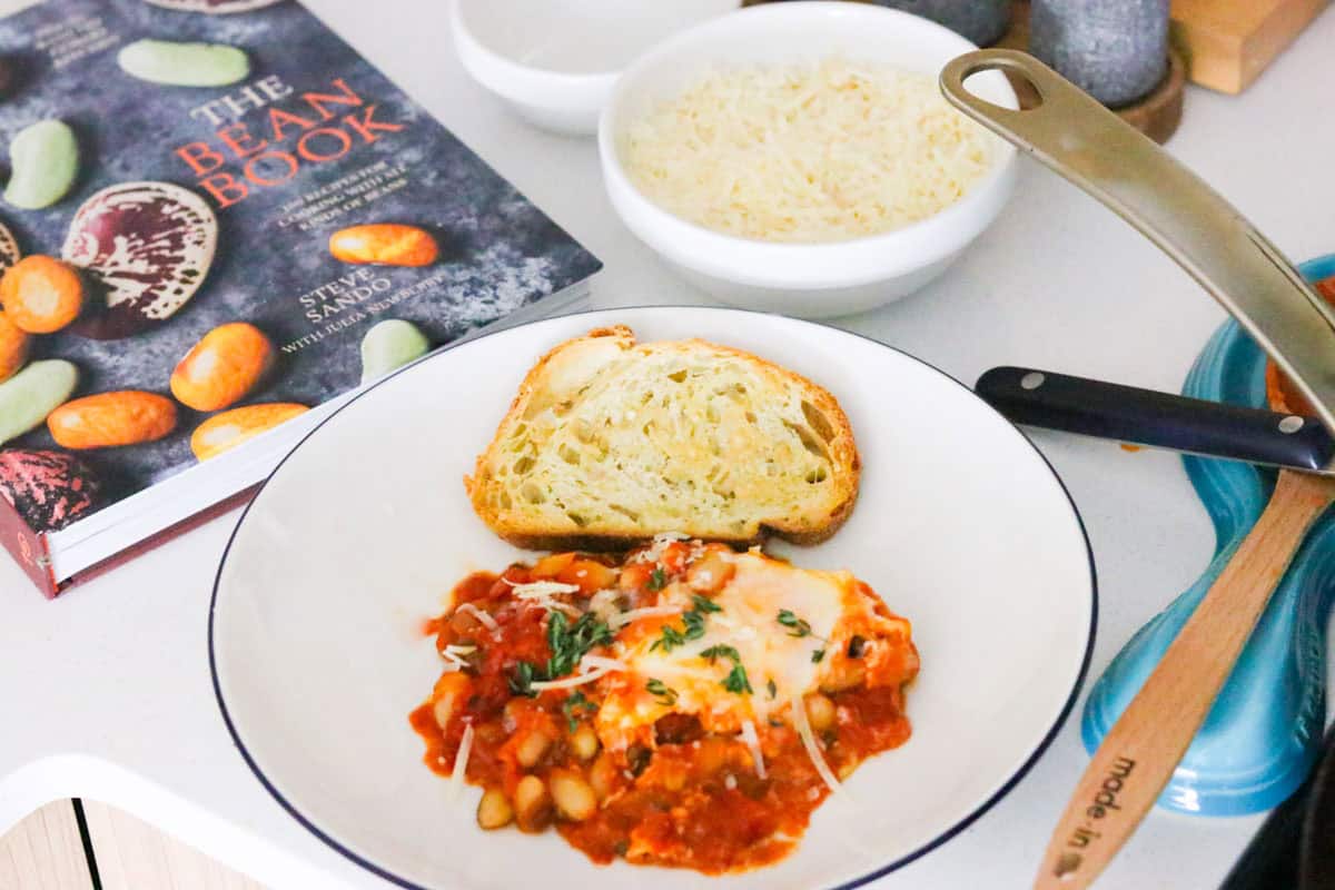 eggs and beans in purgatory beside toasted bread with olive oil and parmesan