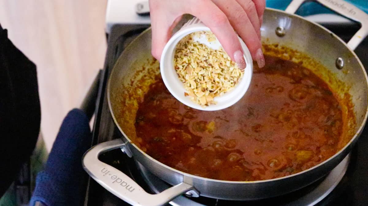 adding crushed almonds to chicken tikka masala sauce