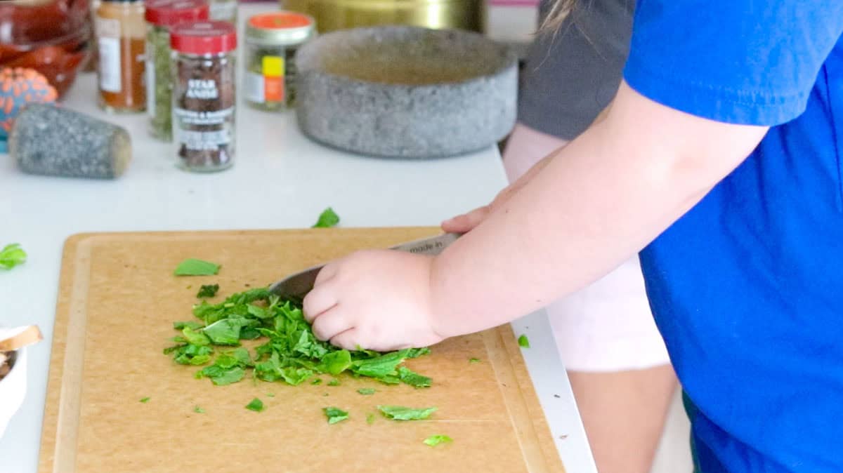 Kat is chopping mint with a utility knife on a cutting board