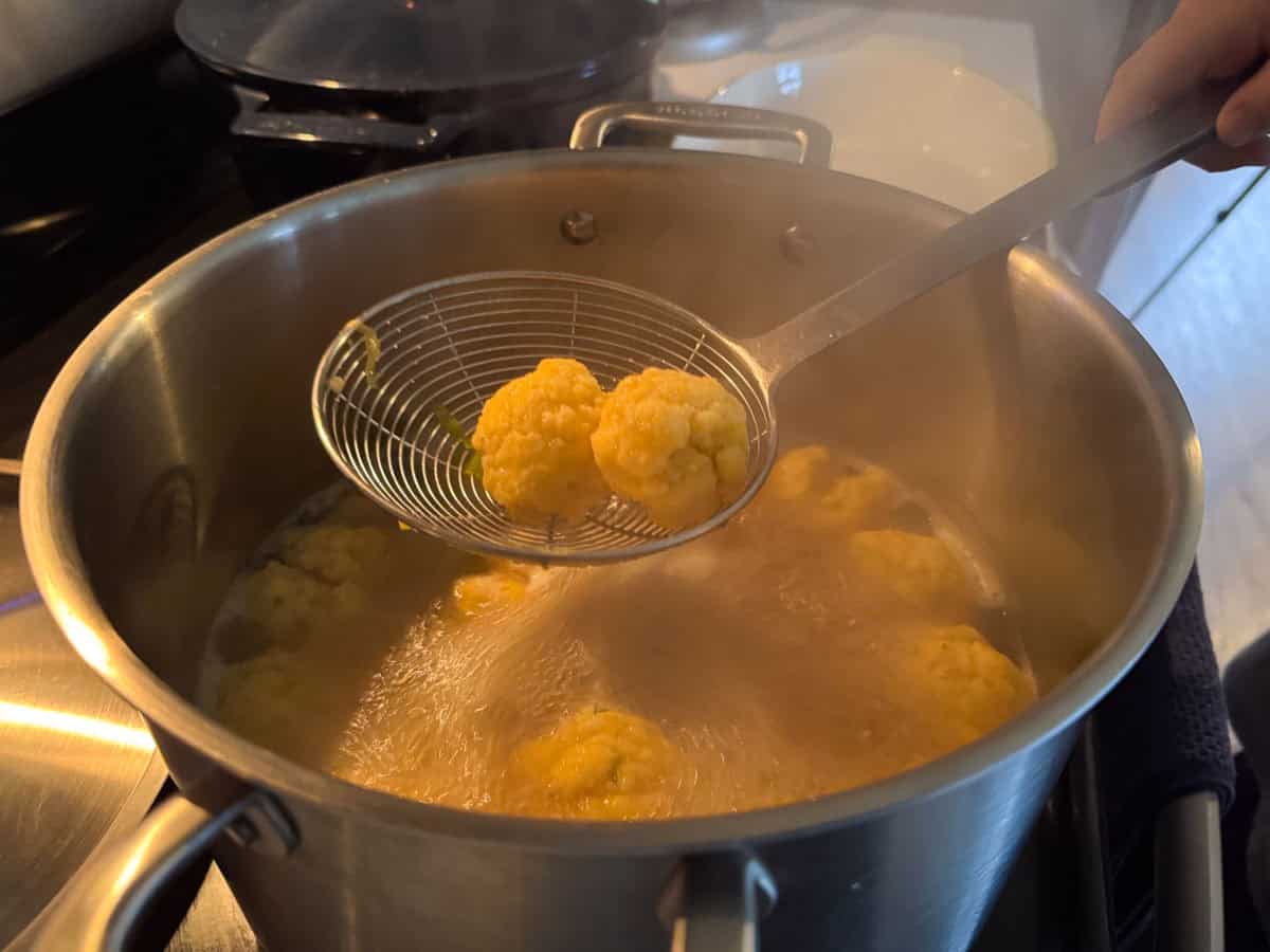 corn dumplings cooking in a stock pot and in a spider strainer