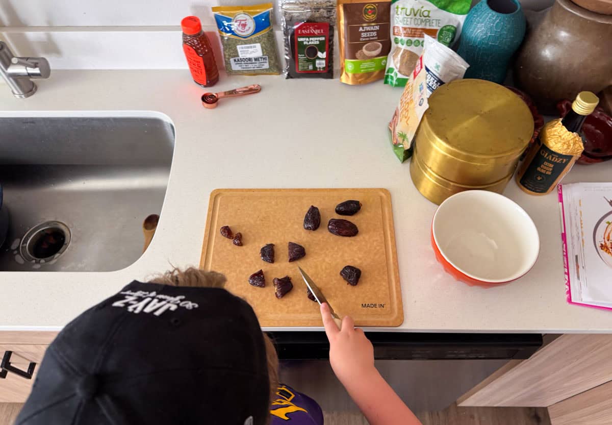 Noah is cutting dates with a paring knife and a cutting board