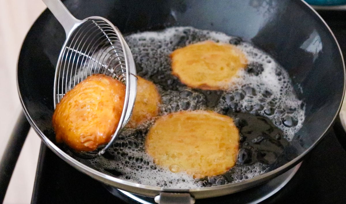 removing zeppole from the wok with a spider strainer