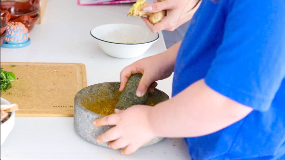 Kat is grinding spices in a molcajete