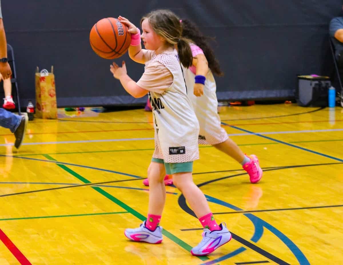 Kat is dribbling up the court in a jr. nba/ymca youth basketball game