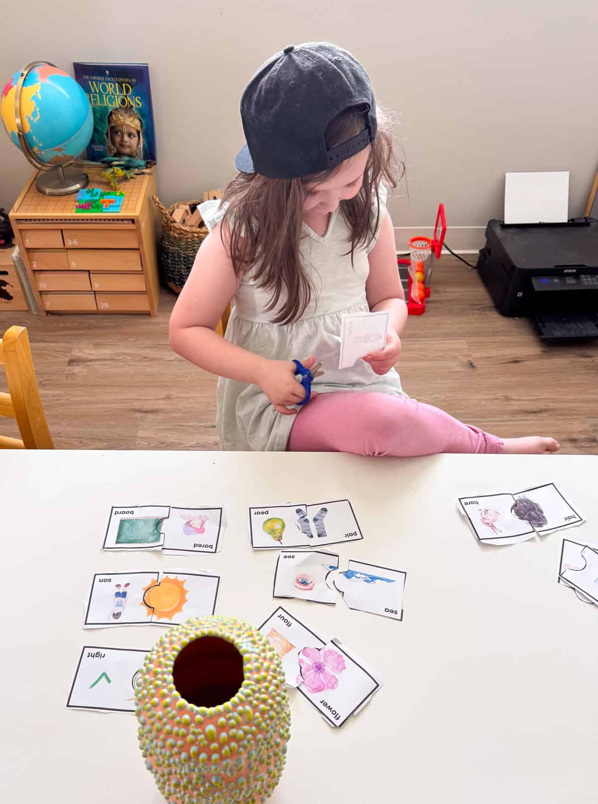 Kat is cutting up Montessori Tube Academy homophones puzzle cards