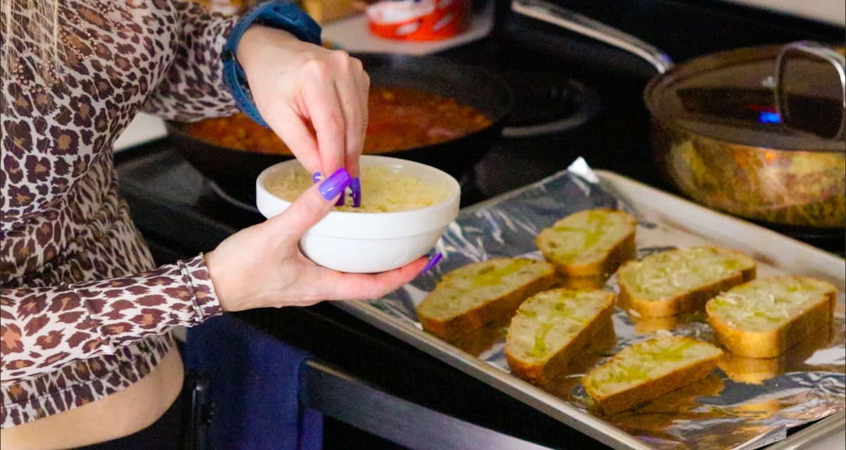 sprinkling parmesan over toasted bread with olive oil