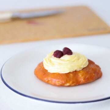 plated zeppole topped with pastry cream and halved dark cherry