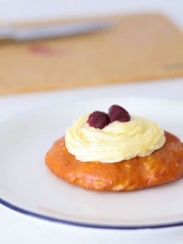 plated zeppole topped with pastry cream and halved dark cherry