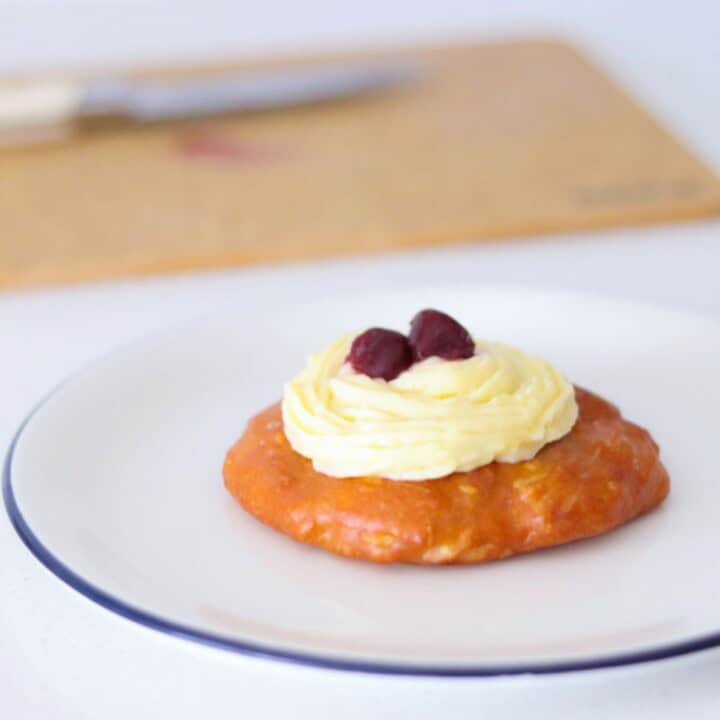 plated zeppole topped with pastry cream and halved dark cherry