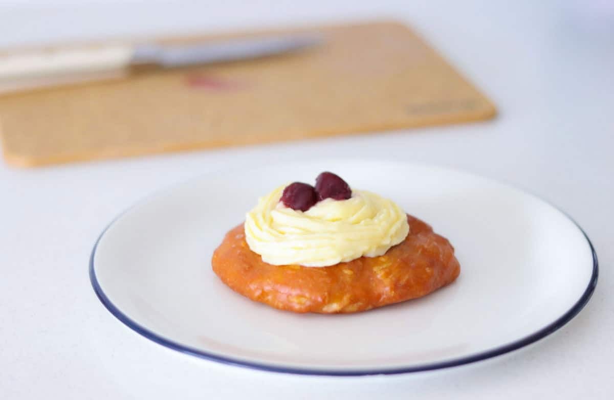 plated zeppole topped with pastry cream and halved dark cherry