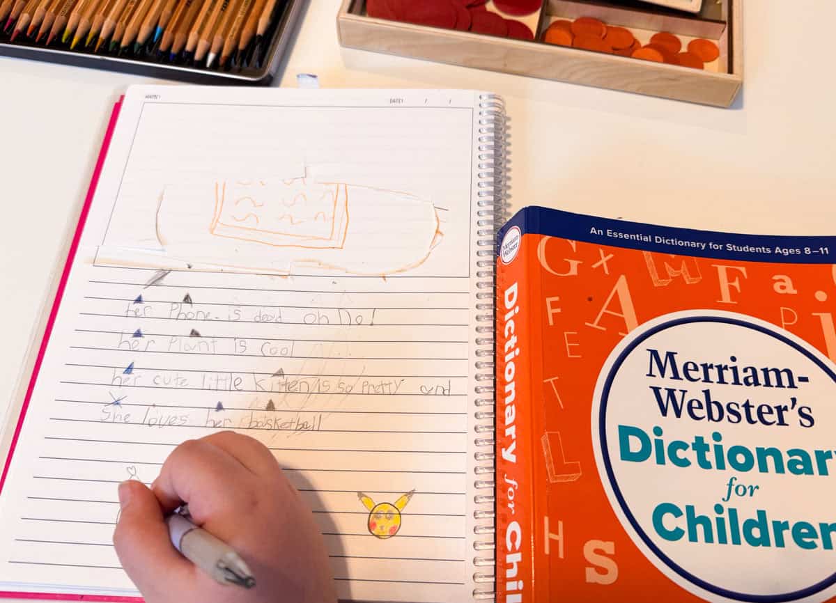Kaia is drawing in her notebook after a possessive adjectives lesson