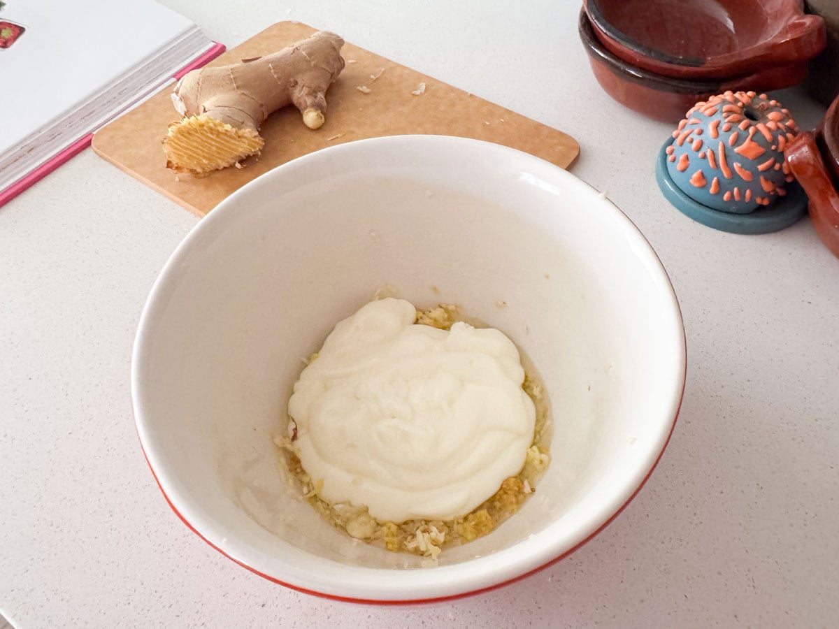 ingredients for making tikka paste in a bowl beside a ginger root