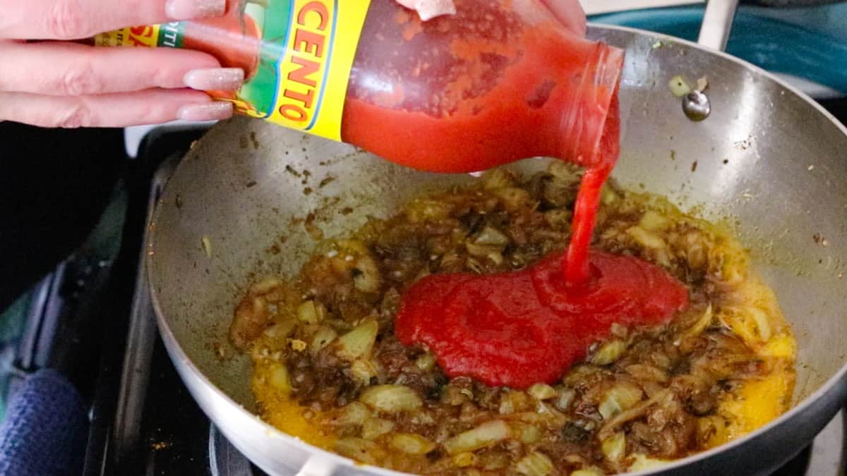 adding tomato puree to a kadai with ctm ingredients