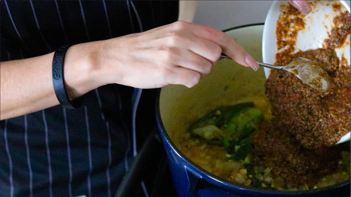 adding black masala paste to the Dutch oven