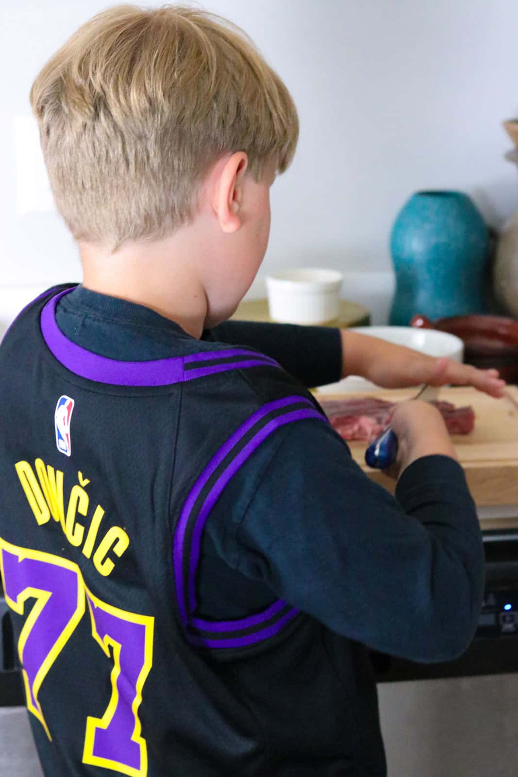Noah is using 2 hands to test out the knife on the lamb shoulder