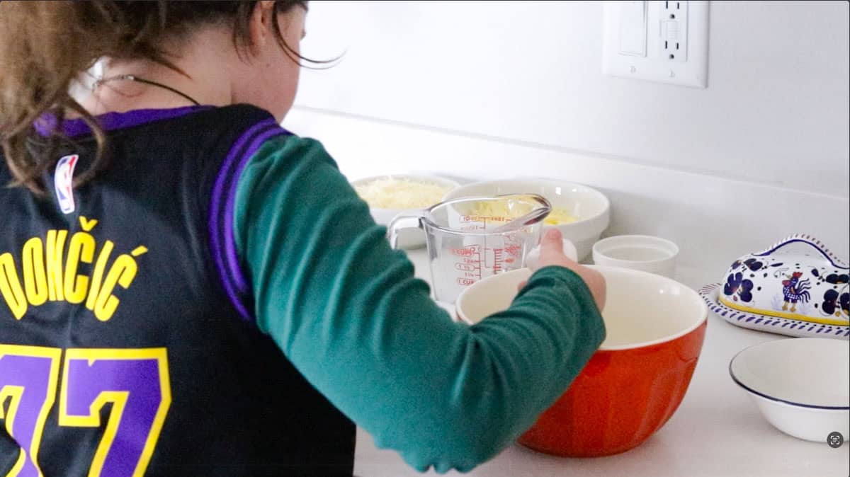Kaia is cracking eggs into a bowl for custard