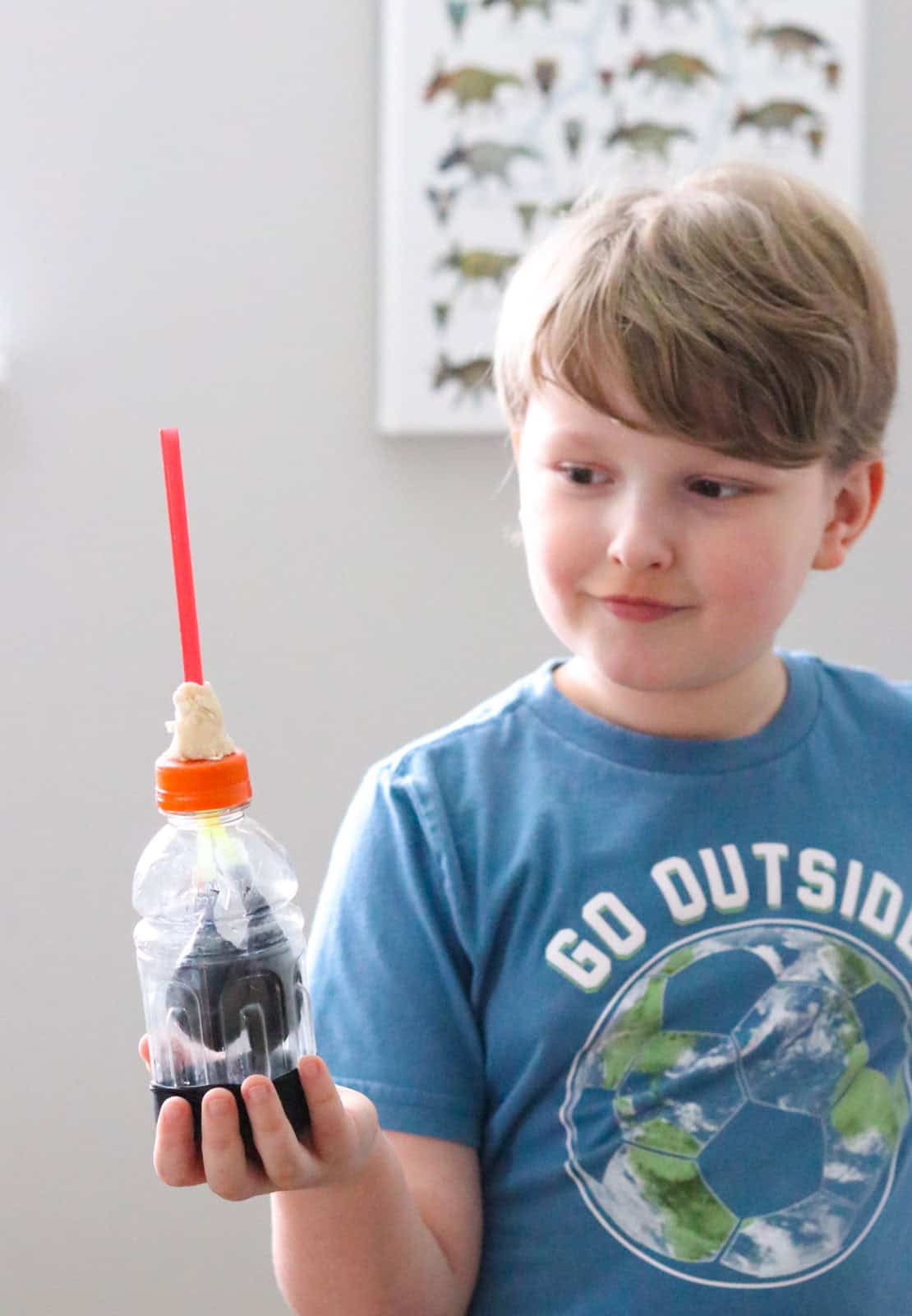 Noah is holding a lung model made from a Gatorade bottle, balloons, straws, and dough