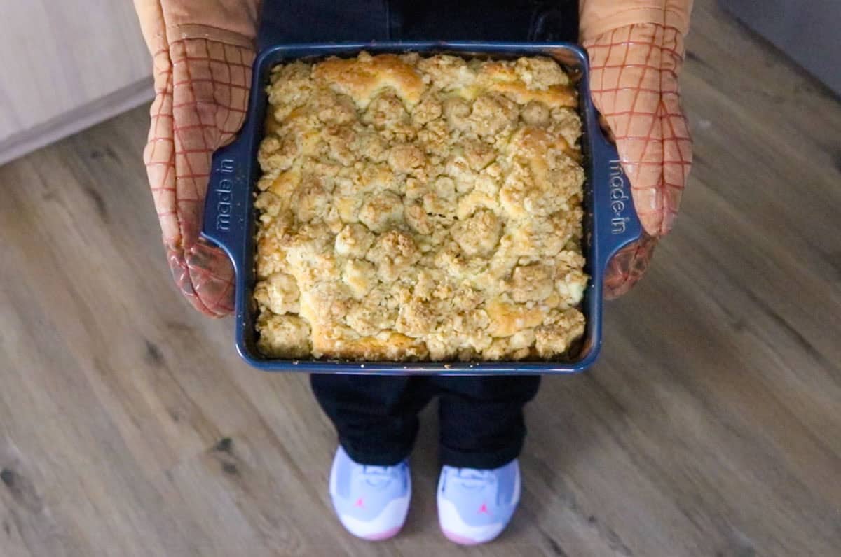 Kristin is holding a new york crumb cake up to the camera