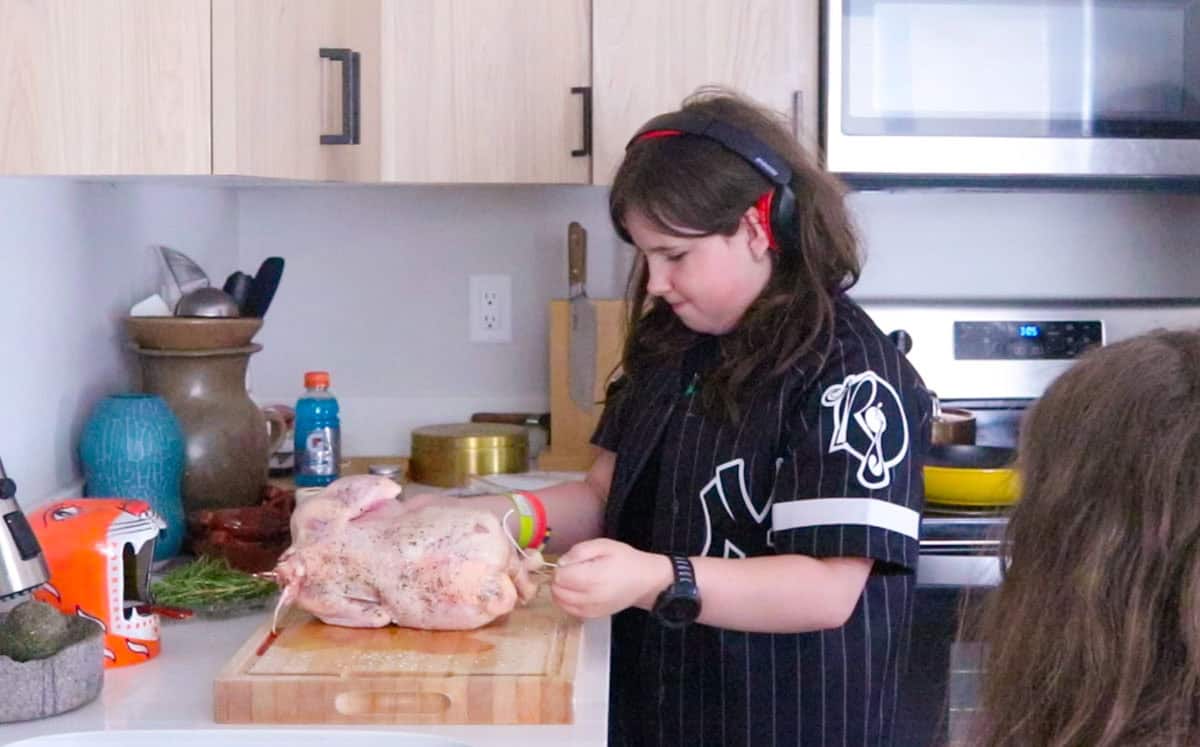 Kaia is tying the chicken's legs together