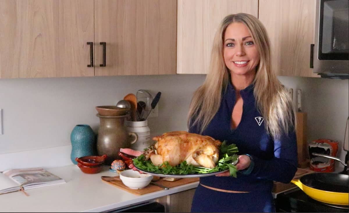 Kristin is holding a whole roasted chicken on a serving platter