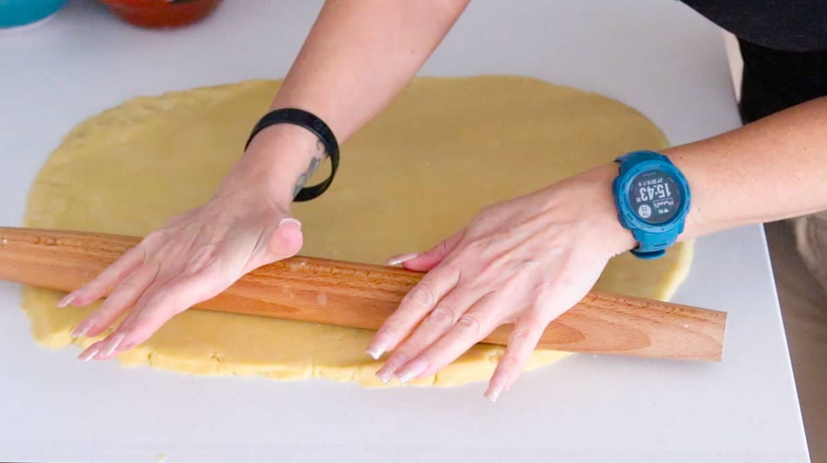 Kristin is rolling out the dough with a rolling pin