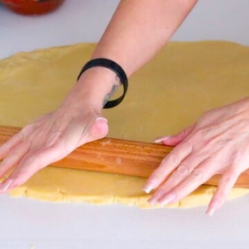 Kristin is rolling out the dough with a rolling pin