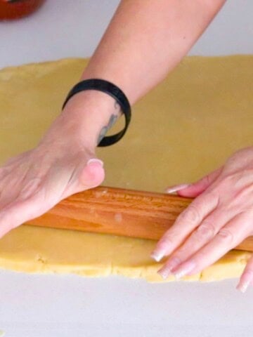 Kristin is rolling out the dough with a rolling pin
