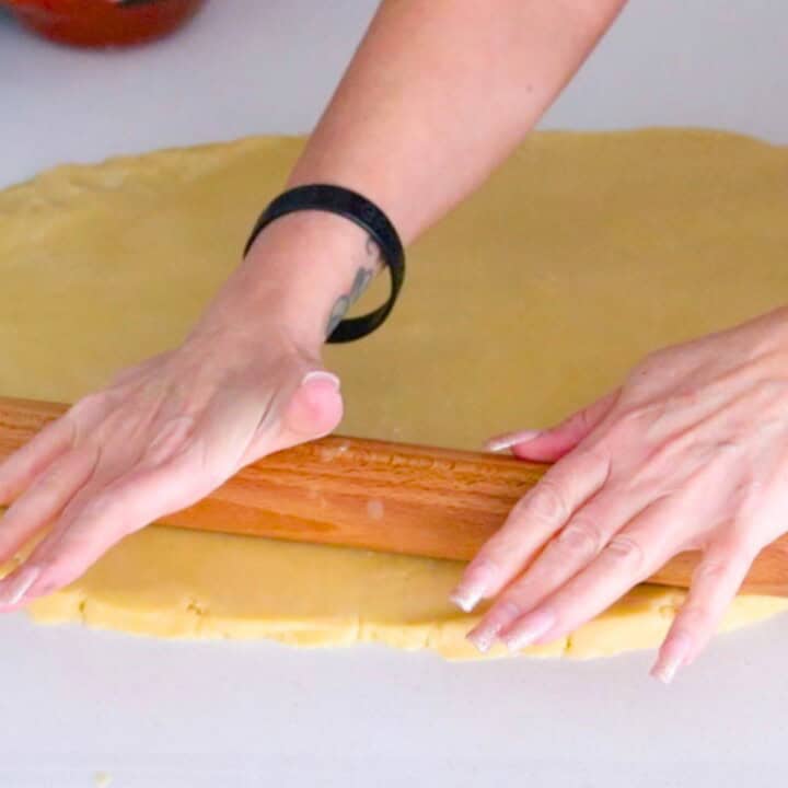 Kristin is rolling out the dough with a rolling pin