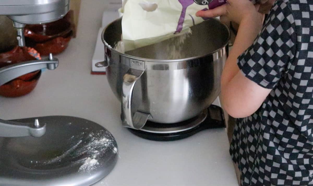 John is weighing flour in a mixing bowl