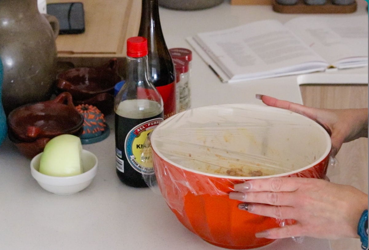 Kristin is covering the marinade with plastic wrap