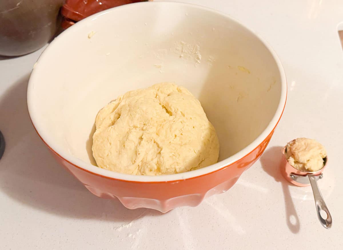 drop biscuit dough in a bowl and a ¼ cup measure with dough in it