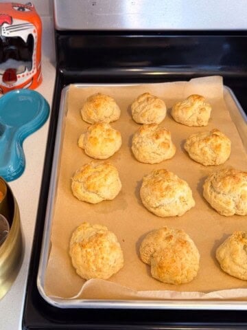 drop biscuits on a baking sheet beside a masala dabba and a bowl