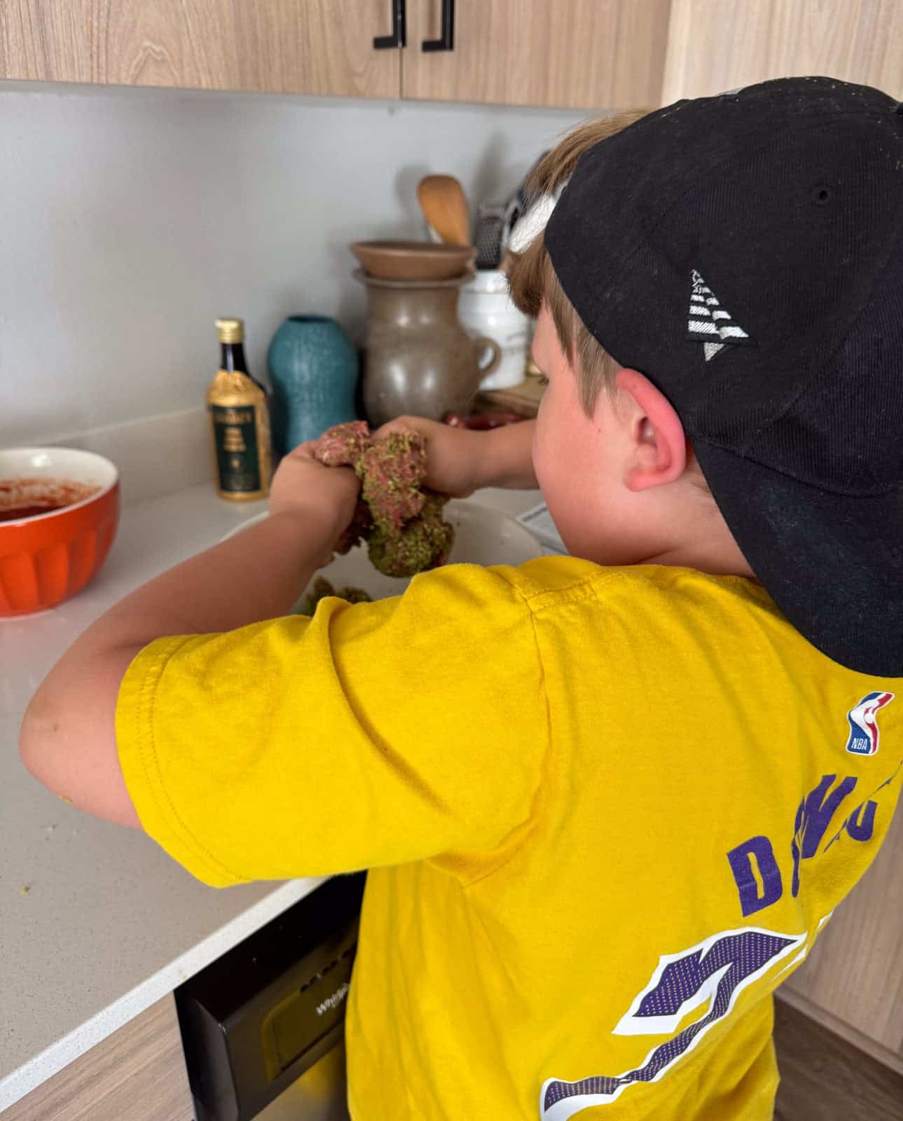 Noah is using his hands to combine the meatball ingredients