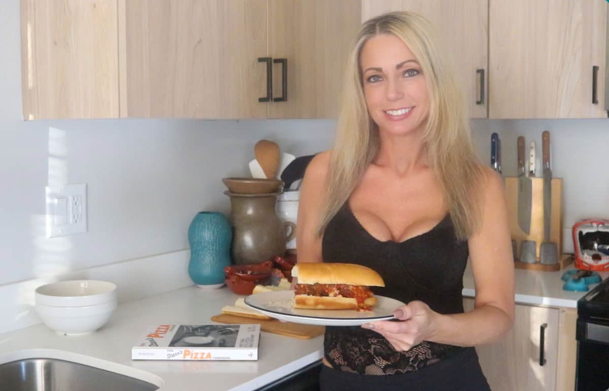 Kristin is holding a plate with a meatball parm hero on it
