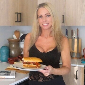 Kristin is holding a plate with a meatball parm hero on it