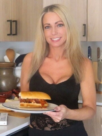 Kristin is holding a plate with a meatball parm hero on it