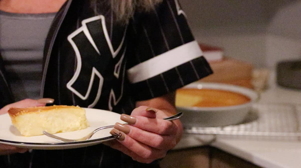 Kristin is holding a plate with a slice of NY cheesecake 