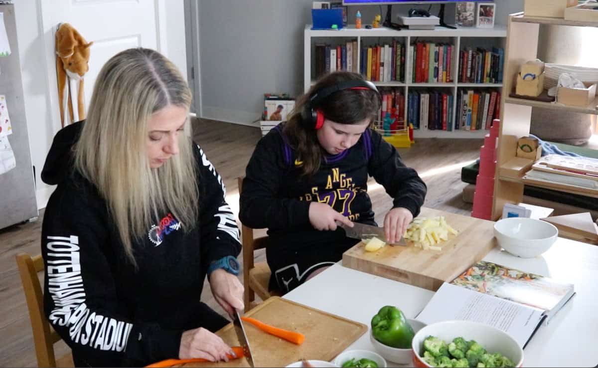 Kristin and Kaia are prepping vegetables using knives and butcher blocks