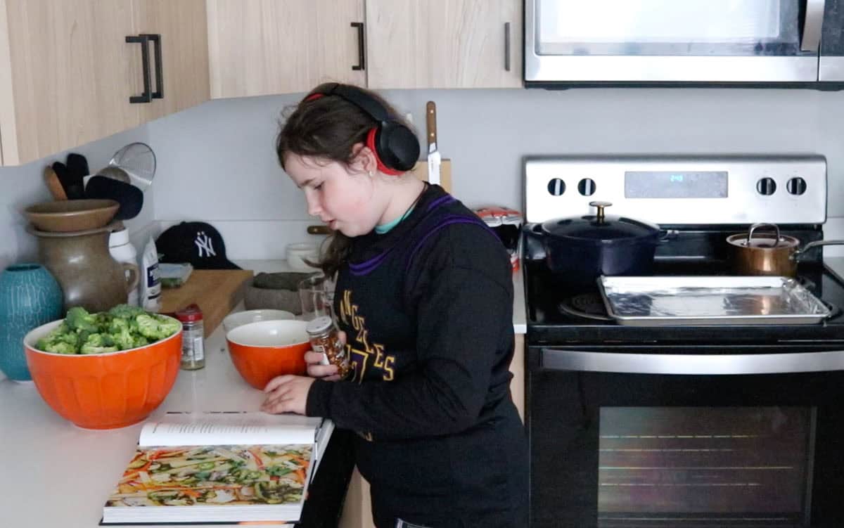 Kaia is reading Veg-Table and holding red pepper flakes